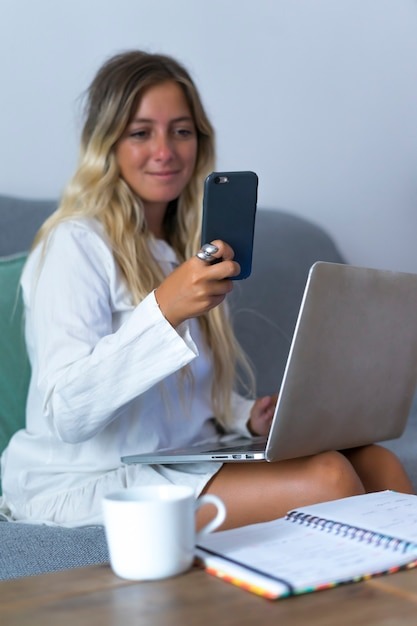 Woman looking at the phone while teleworking