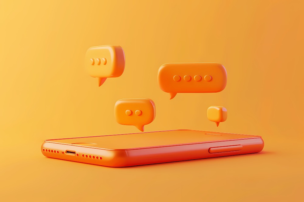 Um smartphone laranja com design minimalista está posicionado em um fundo laranja. Acima do smartphone, há quatro balões de conversa em 3D, também laranja, representando mensagens ou notificações. Esses balões de conversa variam em tamanho e estão flutuando acima do dispositivo, sugerindo uma comunicação ativa ou interações em andamento.